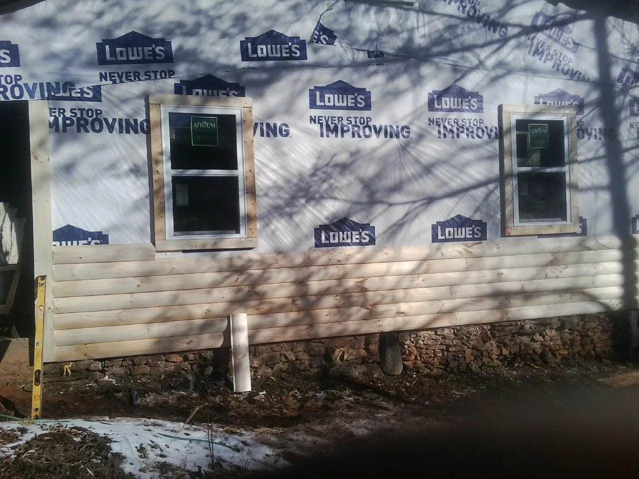 House wrap and new log siding going up on an exterior wall in Youngsville