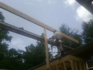 Carpenter setting a ridge beam over a new addition frame — Ice Dam Removal by Roofing Brothers in Youngsville